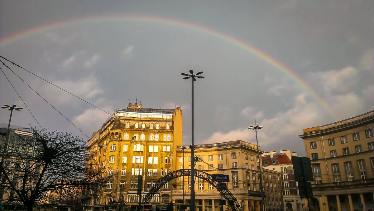 Rainbow arching over city buildings and church towers